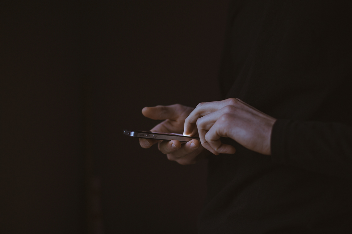 a pair of hands using an iPhone to view a WordPress website in the dark
