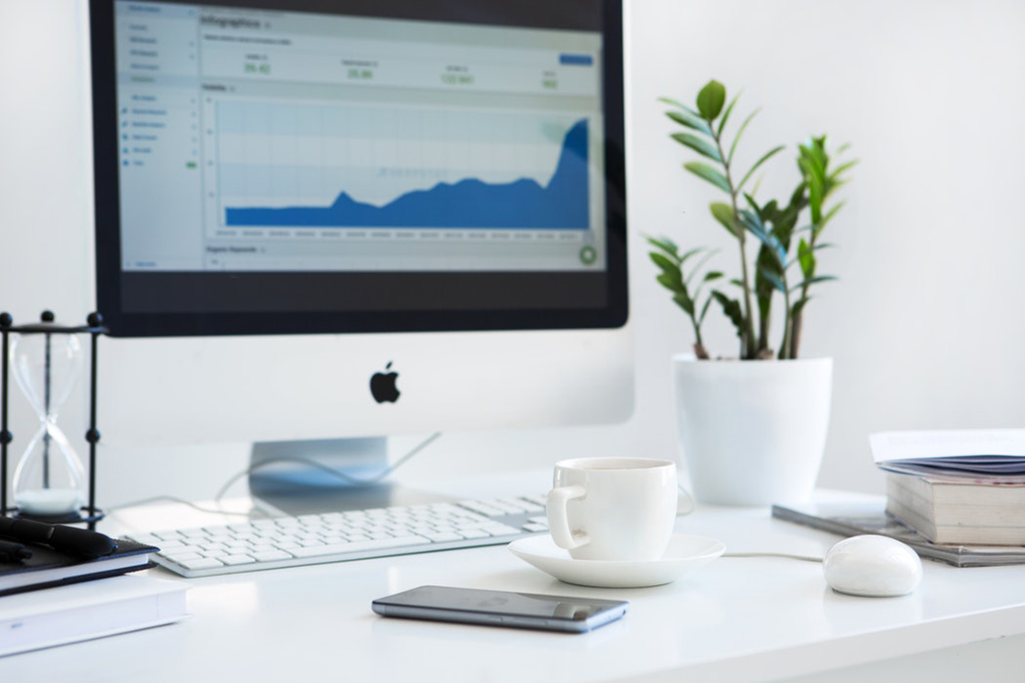 desk with monitor showing an uptick in stats on a graph