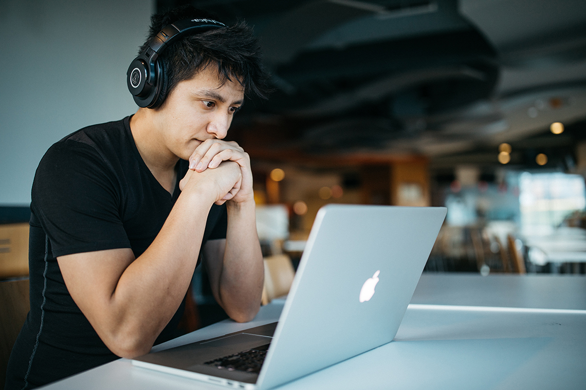 young male doing wordpress training on laptop wearing headphones
