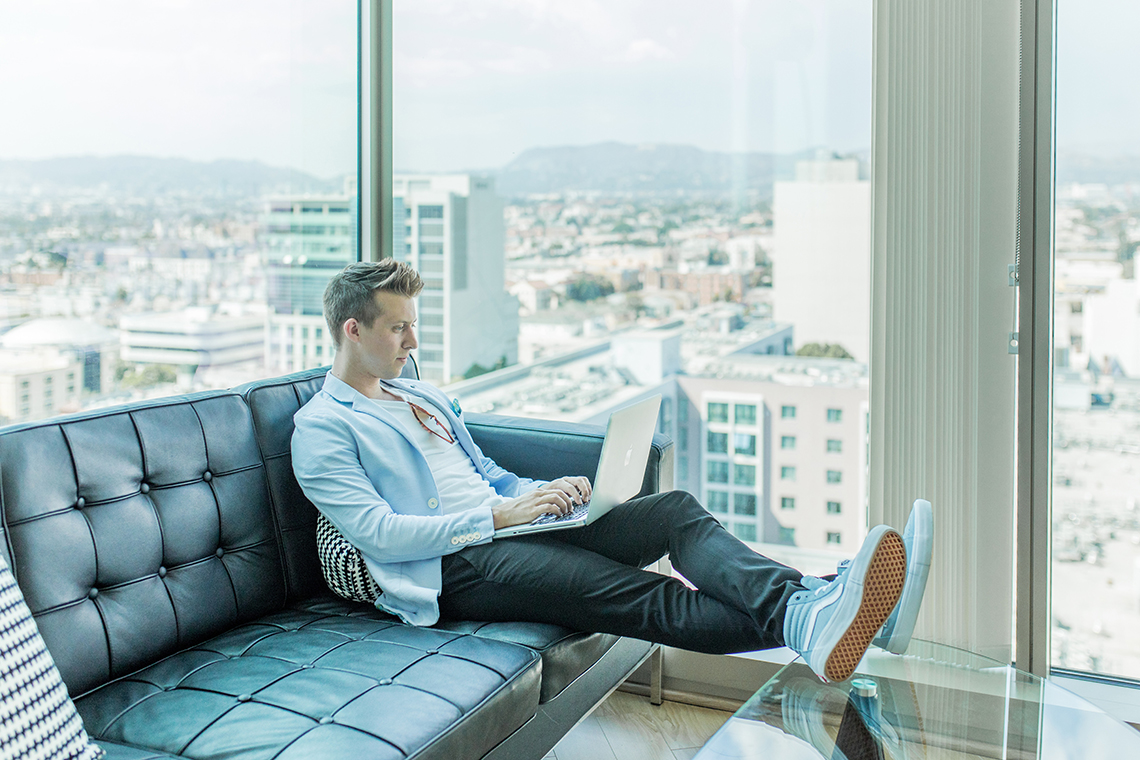 man on sofa with feet up using a laptop to provide a wordpress maintenance service