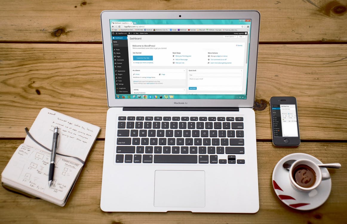 wordpress on a macbook aside a notepad, coffee and phone