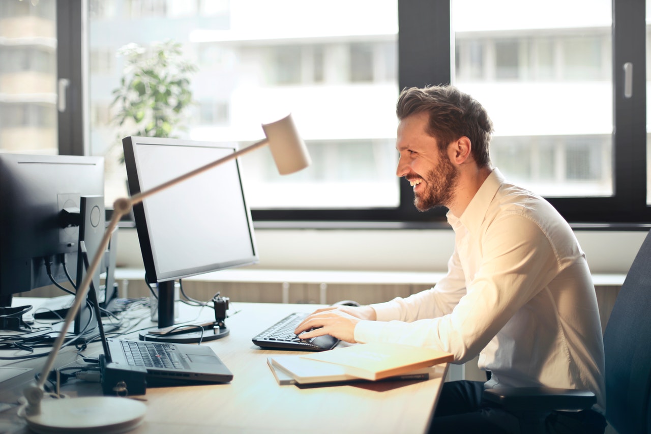 man laughing reading content shared on social media at his desk