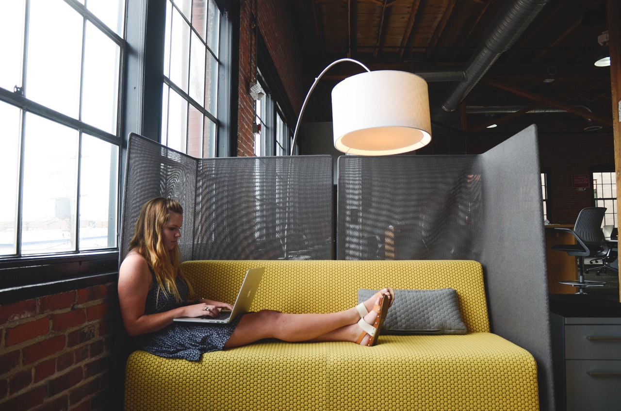 lady sitting relaxed on sofa researching managed wordpress hosting on her laptop